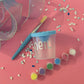 Personalized ready-to-paint party favor set, perfect for birthdays. Includes spill-proof paint cups and soft-bristle brushes with plastic grips. High-quality, non-toxic materials, ideal for kids' creative fun. Customize with names, fonts, and colors for a unique touch.