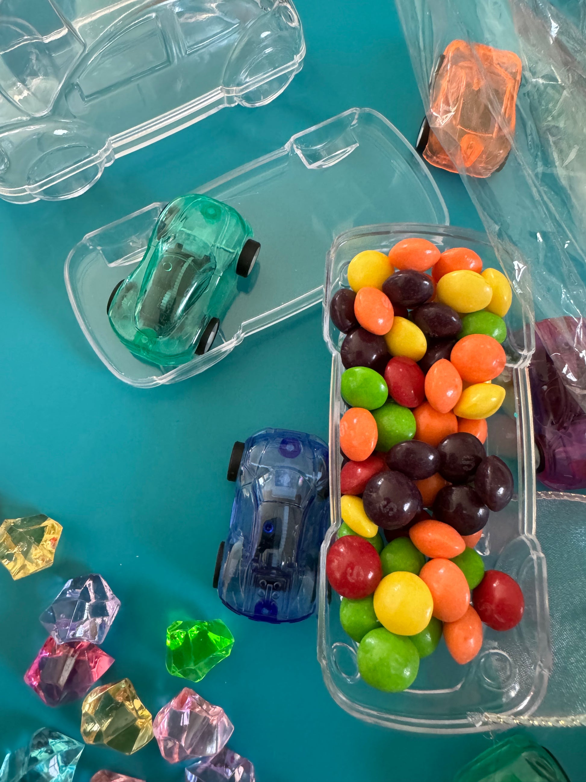 Car-themed candy favors, perfect for birthdays or playdates. Includes car-themed gummies or rainbow Skittles in a car-shaped box. Wrapped in cellophane with optional thank you label. Fun and delicious treat for any party. Custom candy containers available.