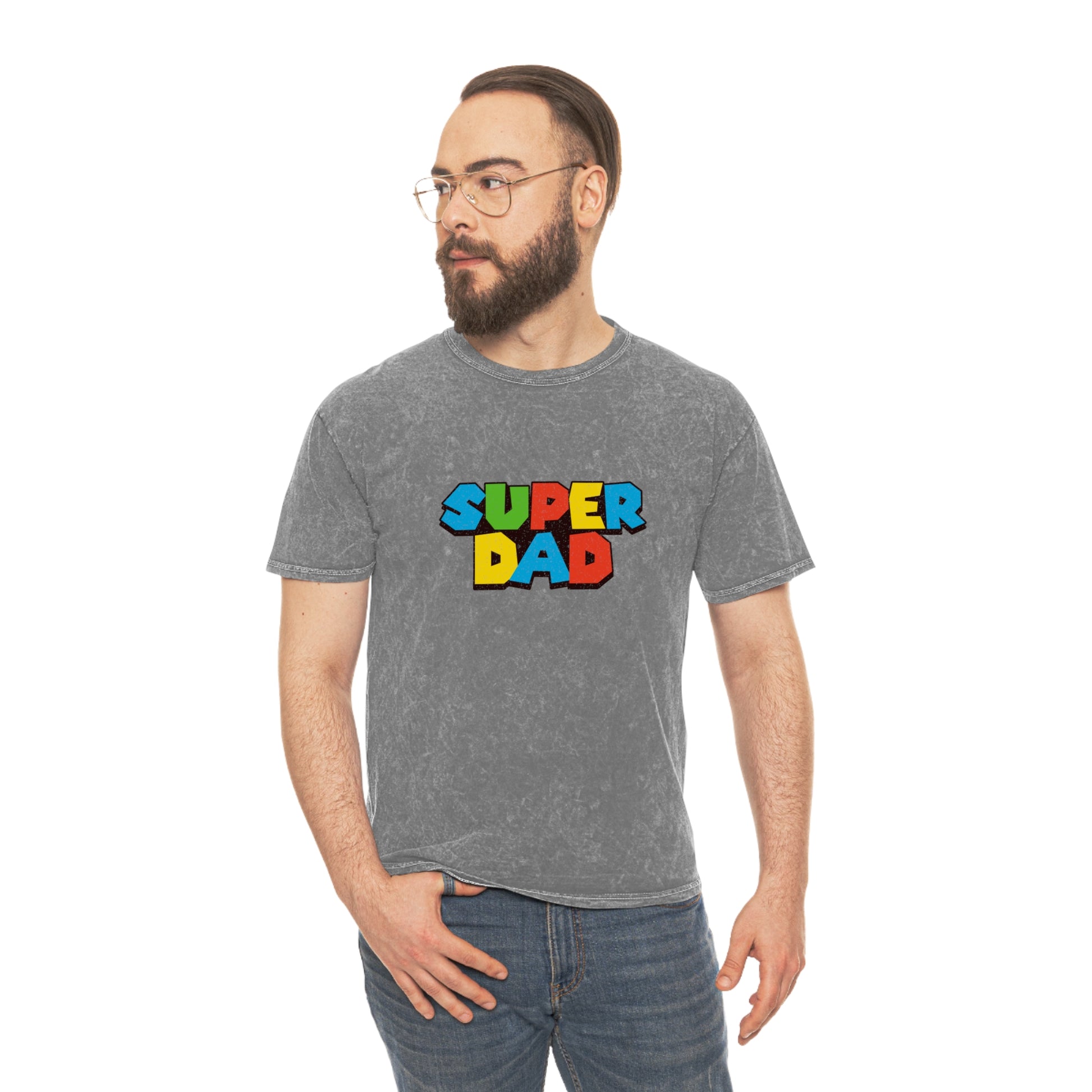 Super Mario-inspired retro 80s Father’s Day shirt for gamer dads. Soft 100% cotton with a nostalgic mineral wash effect, featuring a classic crewneck and 'SUPER DAD' graphic in colorful block letters. Available in black, gray, navy, and purple, men’s sizes small to 2XL. Perfect geeky dad gift for birthdays or Father’s Day.