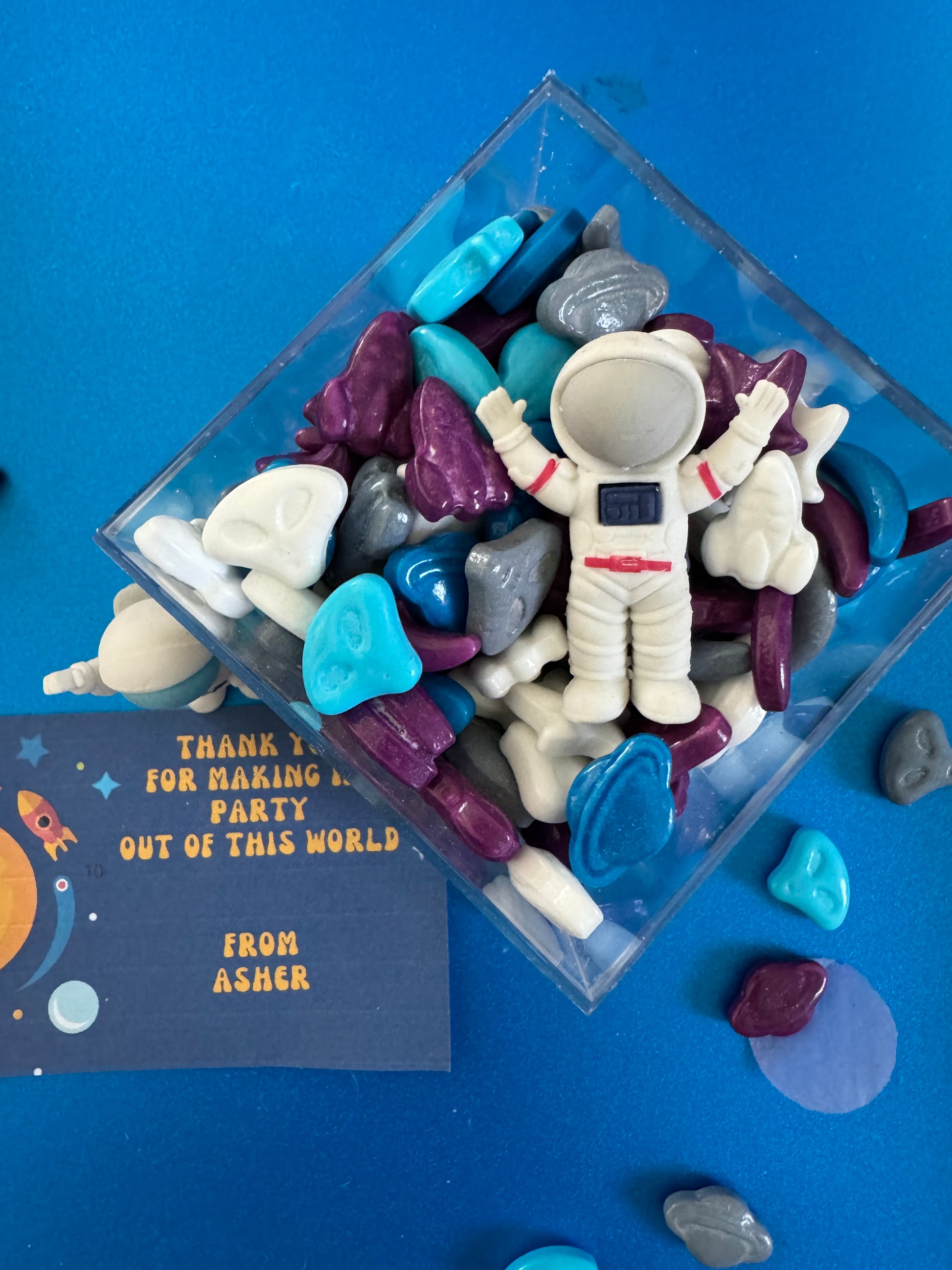 Space-themed party favor boxes filled with candy shaped like planets, aliens, UFOs, and spaceships. Perfect for astronaut birthday parties, classroom space day, or cosmic-themed events. Clear box with optional personalized gift tag. Great for boys, girls, and space lovers of all ages.