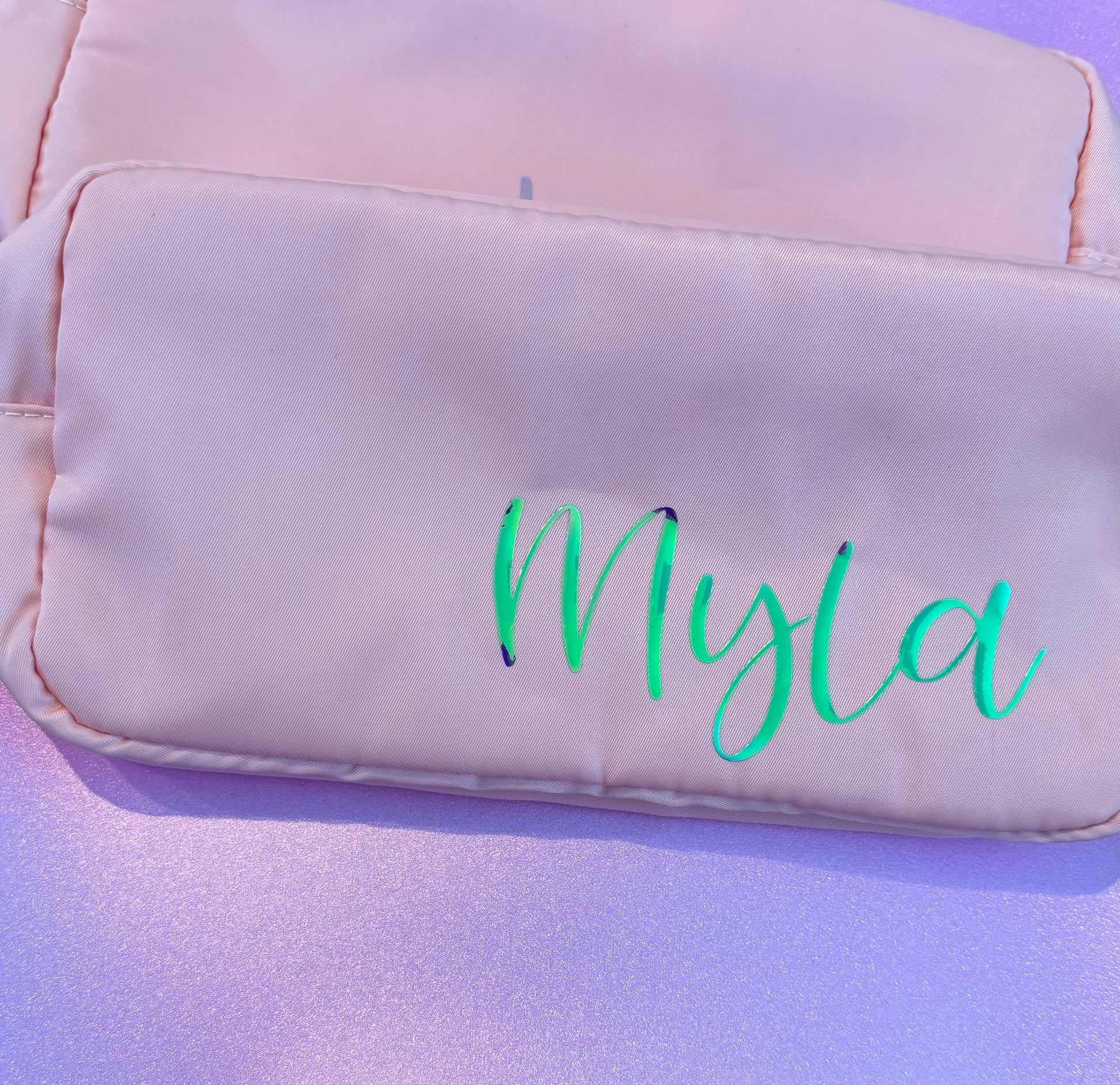 Personalized cosmetic pouch with zipper, featuring custom name, initials, or trendy icons. Lightweight and durable, available in neon or neutral colors with gold zippers. Size: 10" long x 5" wide x 3" deep. Perfect for summer slumber parties, travel, school, or as a makeup organizer. Great gift for girls, bridesmaids, or team members.