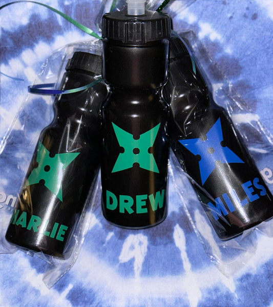 Personalized black hydration bottles with vibrant, ninja-inspired star symbols and names in colorful, glossy or sparkly finishes. Perfect for kids’ birthday parties, school events, or everyday adventures, these durable bottles make unique gifts or party favors. Sleek design, customized for each child, and wrapped with decorative ribbons for easy gifting.