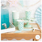 Mermaid Tail Paper Party Cups with adhesive tail and aqua foil accents, perfect for under-the-sea themed celebrations. Includes 8 cups per package, 12 oz capacity, measuring 4.5" tall and 3.5" round at the top