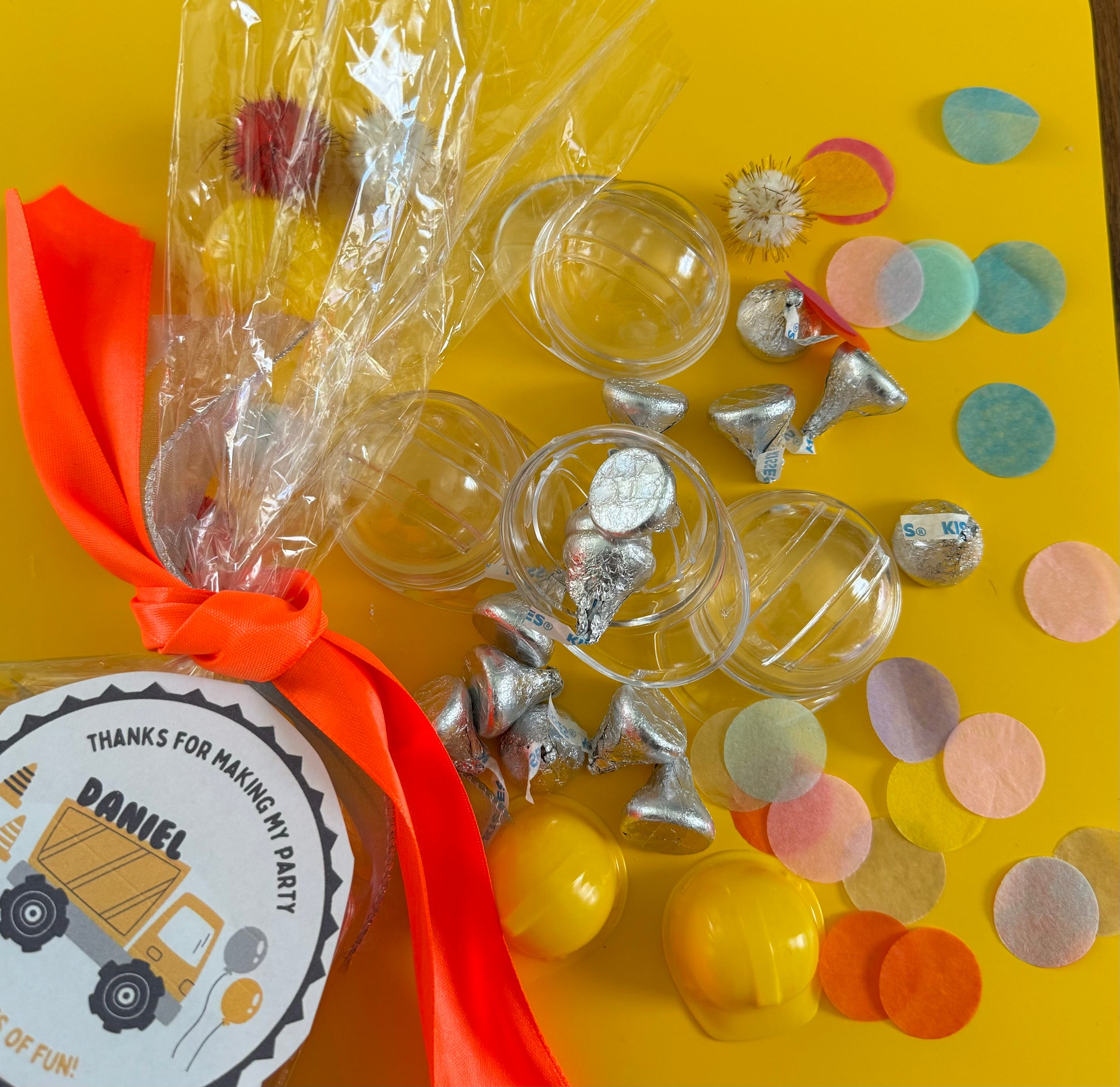 Construction-themed candy favor in plastic helmet containers with chocolate kisses and themed labels. Wrapped in cellophane with optional thank you label. Ideal for construction-themed parties and events.