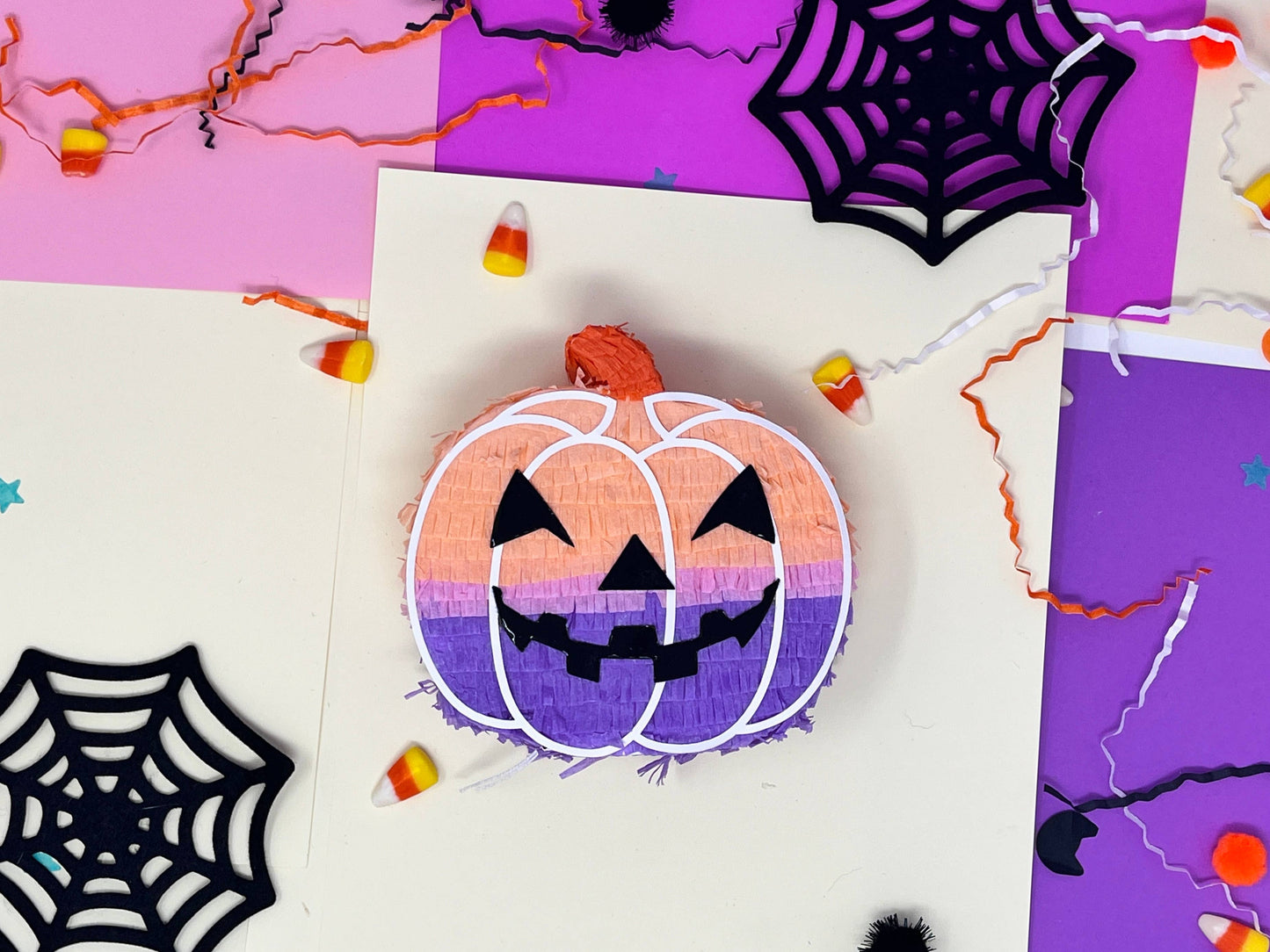 Groovy mini pumpkin piñata with orange, lavender, and pink colors for a boho Halloween vibe. Measures 5 inches tall and long, with a 1.5-inch width, featuring a trap door for treats. Perfect for Halloween decor or party favors for kids and family.