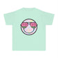 Kids’ summer t-shirt with a leopard print smiley face and watermelon sunglasses. Soft, durable cotton, available in youth sizes XS-XL. Perfect for summer activities.