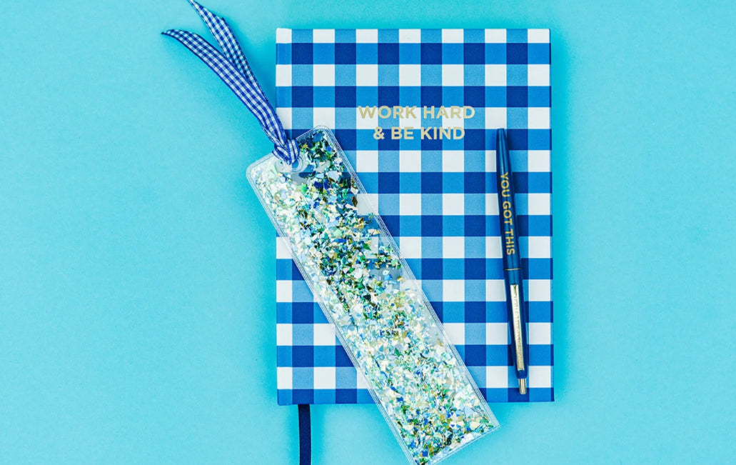 Delightful confetti bookmark for books, planners, or Bibles, measuring 2" x 7". Made of clear plastic with blue and green confetti, finished with a blue gingham ribbon.