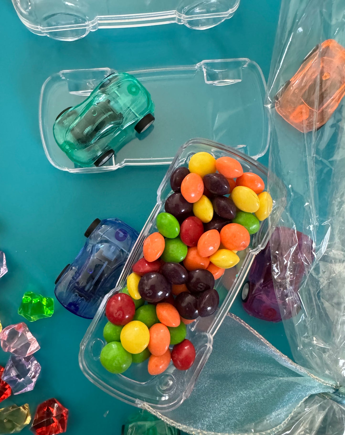 Car-themed candy favors, perfect for birthdays or playdates. Includes car-themed gummies or rainbow Skittles in a car-shaped box. Wrapped in cellophane with optional thank you label. Fun and delicious treat for any party. Custom candy containers available.