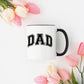 White ceramic mug, black handle and interior, perfect for coffee, tea, or lattes, available in one or two-sided designs, 11 oz capacity, 3.75" tall x 3.25" wide, dishwasher safe, microwave safe, classic style for daily use, ideal gift or personal use.