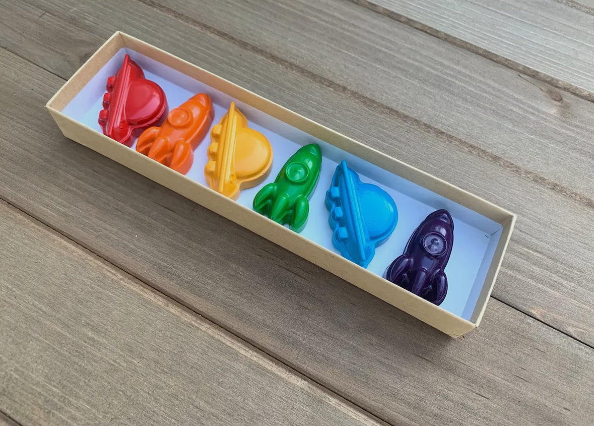 Awesome space-themed crayon gift set containing 6 non-toxic crayons in an 8" x 2" box. Perfect for stocking stuffers, Easter baskets, party favors, and classroom gifts. Made from recycled and upcycled materials, featuring assorted colors including red, green, blue, and more.