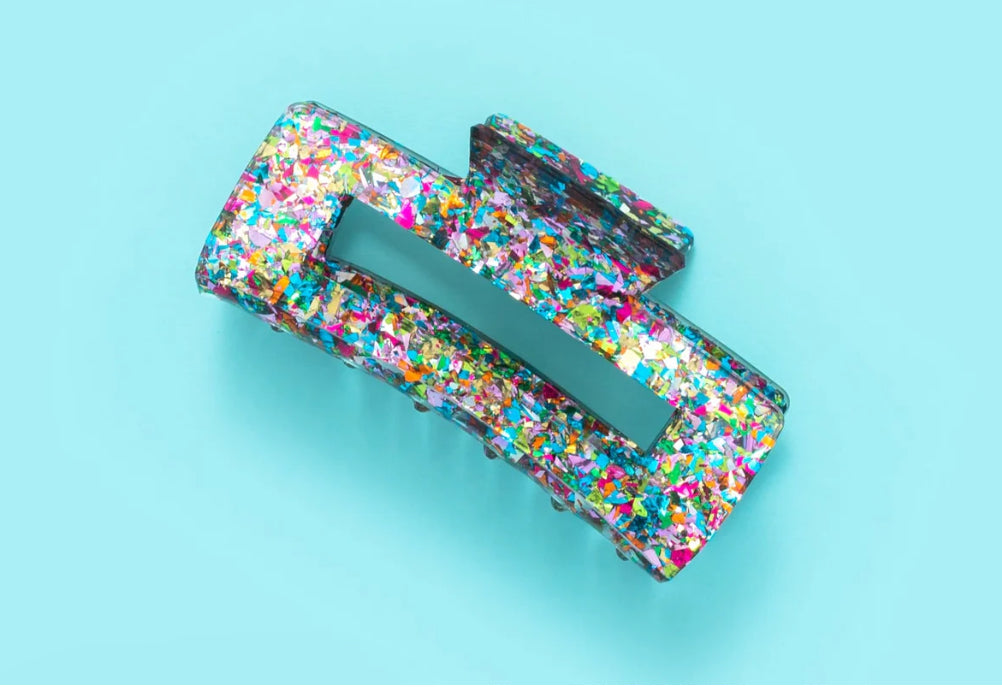 Sparkly 4-inch claw clip featuring colorful confetti, perfect for holding hair securely while adding a touch of style to any outfit. Ideal for everyday wear or special occasions, this durable hair accessory is a must-have for fashion-forward individuals.