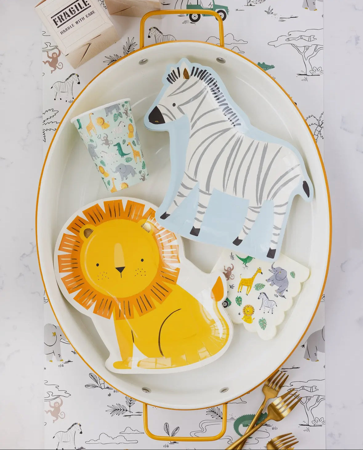 Zebra-shaped paper plates featuring a whimsical zebra illustration with gold foil accents. Includes 8 plates, approximately 11" wide and 10" tall. Perfect for adding a fun and wild touch to a safari-themed birthday party table decor.