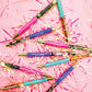 A festive pile of colorful pens with vibrant confetti on top, adding a playful touch to your desk.