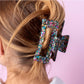 Sparkly 4-inch claw clip featuring colorful confetti, perfect for holding hair securely while adding a touch of style to any outfit. Ideal for everyday wear or special occasions, this durable hair accessory is a must-have for fashion-forward individuals.