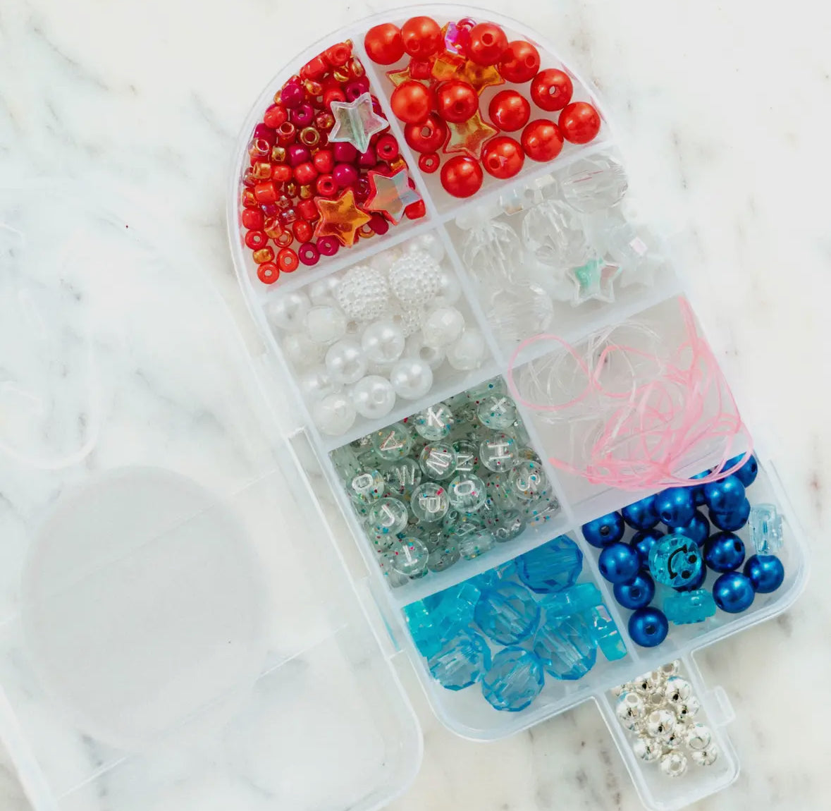 DIY jewelry bead kit featuring red, white, clear, and pearl beads, along with glitter alphabet beads and pink and clear string. Perfect for creating bracelets or necklaces. Made by a small, women-owned business. Warning: contains small parts.