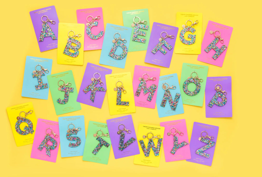 Personalize your accessories with our Confetti Letter Keychains. Each keychain features a 3" x 3" acrylic letter with confetti sprinkled inside, ensuring no shedding. Includes a gold metal keyring and gold foil imprinting on a 3.6" x 6.5" backer card.