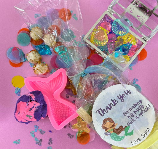 Mermaid Sensory Kit featuring Purple/Pink swirl glitter dough with mermaid confetti, enclosed in a gold or silver treasure chest. Includes gems, seashells, glitter pompoms, and a cookie cutter for creative play. Perfect for sensory development in kids