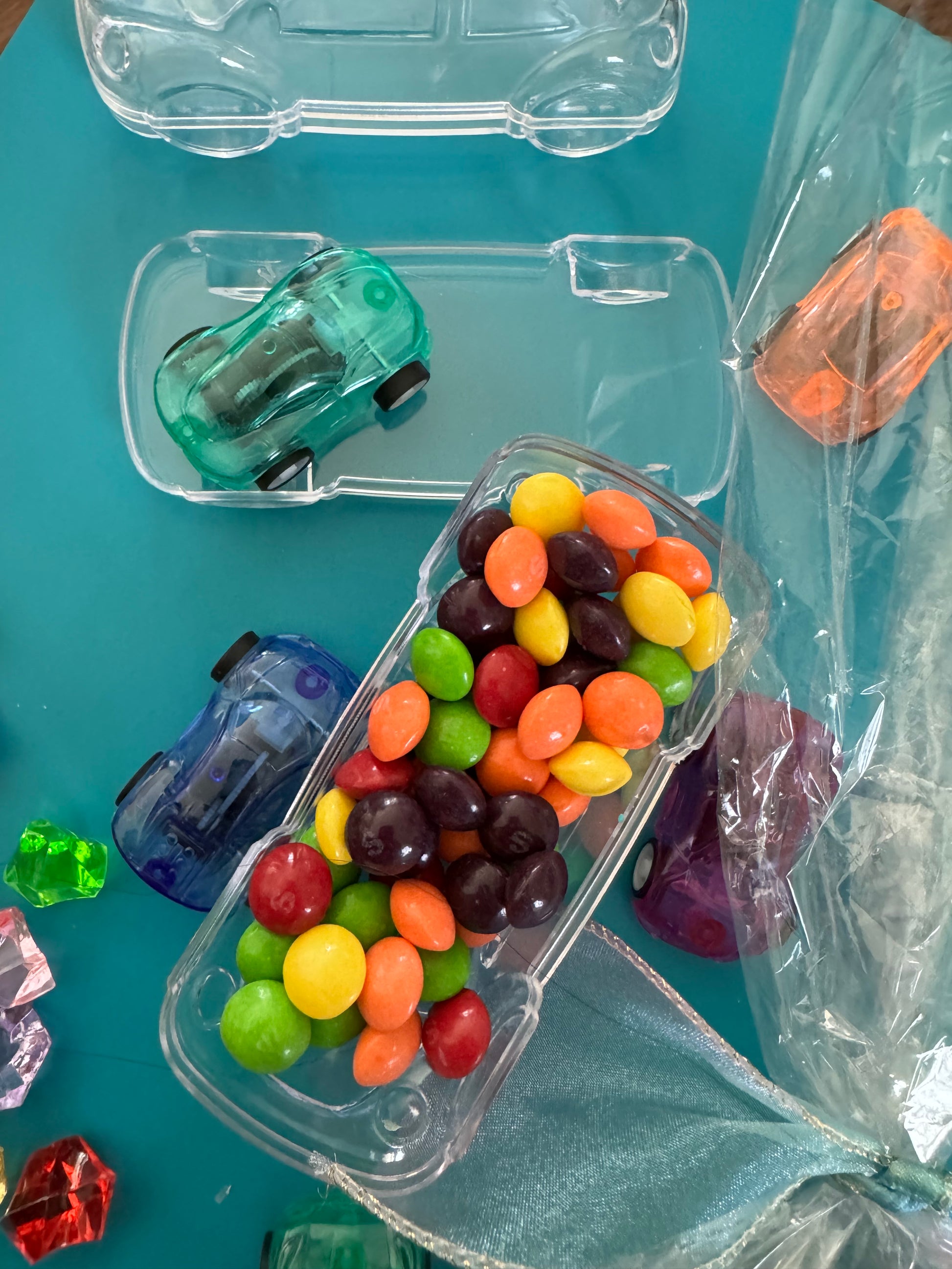 Car-themed candy favors, perfect for birthdays or playdates. Includes car-themed gummies or rainbow Skittles in a car-shaped box. Wrapped in cellophane with optional thank you label. Fun and delicious treat for any party. Custom candy containers available.