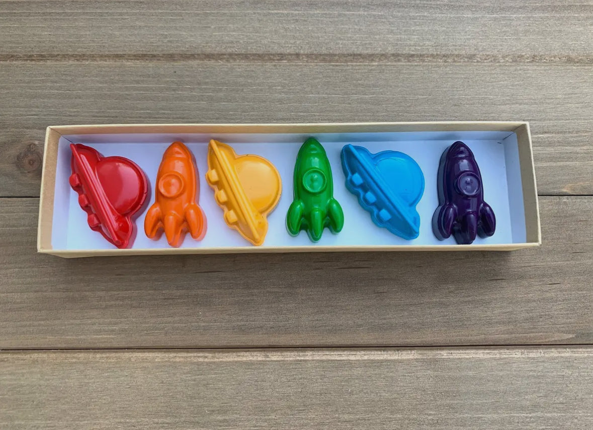 Awesome space-themed crayon gift set containing 6 non-toxic crayons in an 8" x 2" box. Perfect for stocking stuffers, Easter baskets, party favors, and classroom gifts. Made from recycled and upcycled materials, featuring assorted colors including red, green, blue, and more.