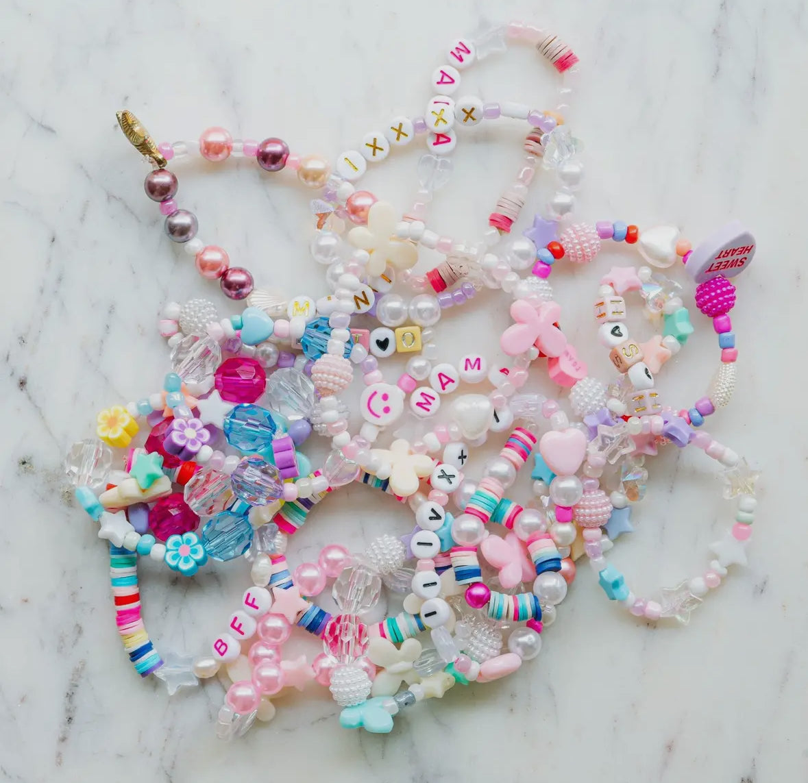 Little Miss Unicorn Bead Kit featuring glitter alphabet beads, iridescent star and heart beads, and various other beads, along with pink and clear string. Perfect for creating custom bracelets or necklaces. WARNING: Contains small parts. Made by women-owned small business, STACKS!