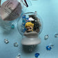 Frozen-themed sensory kit featuring snowy blue/white glitter swirl dough in a snow globe, Frozen figurines, soft snowy trees, snowmen, and glitter pompoms. Perfect for sensory development and creative play. Ideal for kids 3 and up. Choking hazard warning.