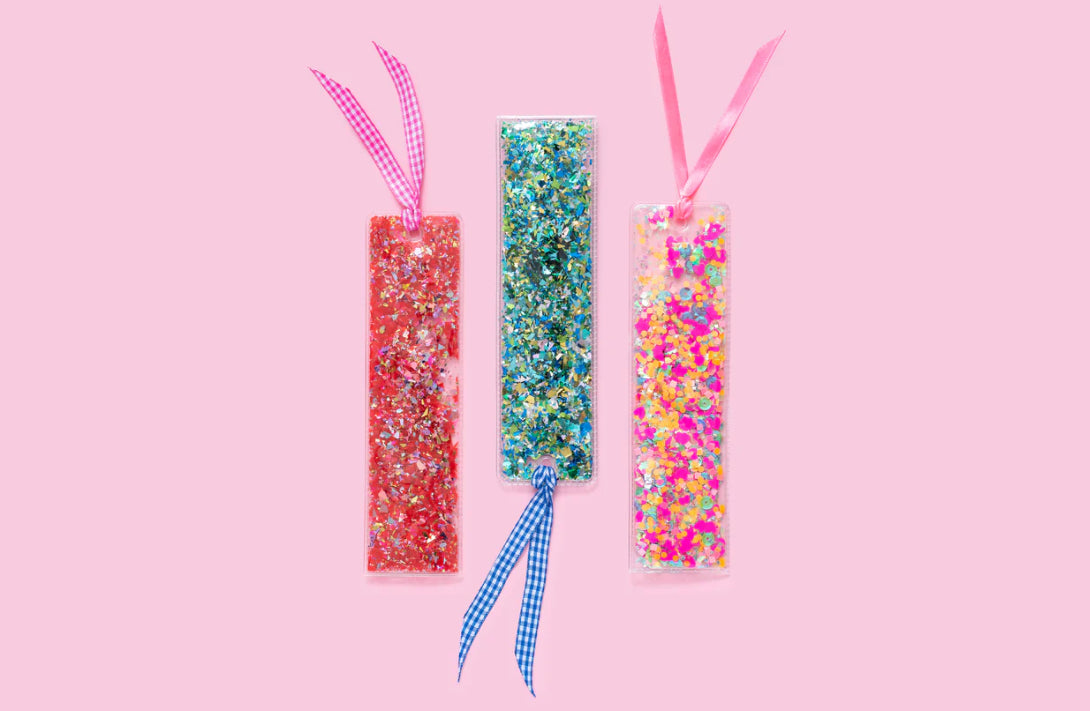 Fun confetti bookmark, perfect for book lovers. Measures 2" x 7", made from clear plastic with hand-selected, colorful confetti inside. Tied with a pink ribbon for an added touch of charm. Imported.