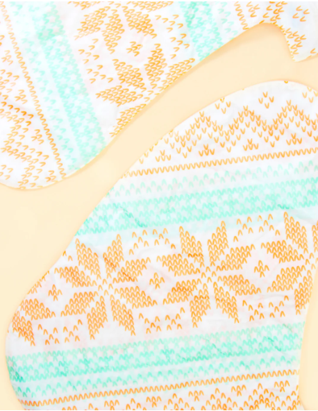 Cozy Socks Smoothing Foot Masks enriched with cocoa butter and peppermint oil, designed to hydrate and heal dry, cracked feet, featuring a fun fair isle print for a festive and relaxing self-care experience.