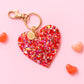 a heart shaped keychain on a pink background