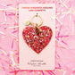 a heart shaped keychain on a pink background