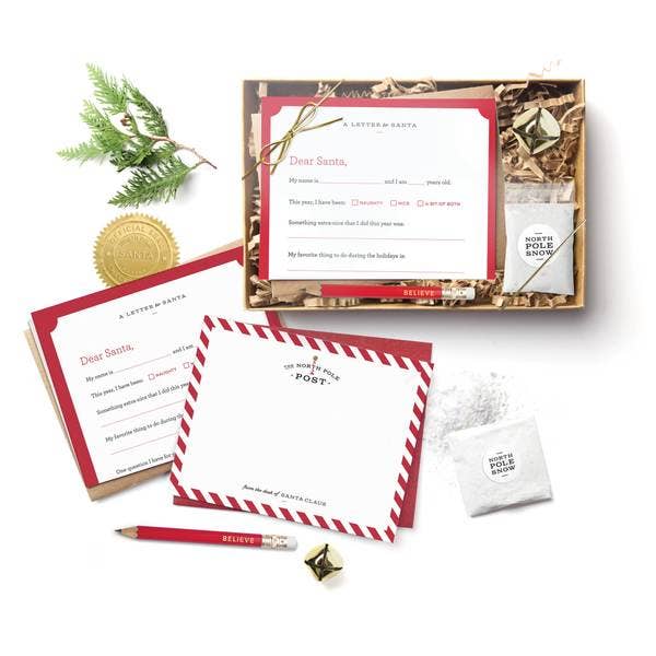 Christmas letter kit with 3 fill-in-the-blank letters to Santa, kraft envelopes, postcards, Santa seals, jingle bell, mini pencil, magic snow, and instructions, all packaged in a kraft box with clear top and golden bow, sustainably made in the USA. Perfect for creating Christmas magic for kids.